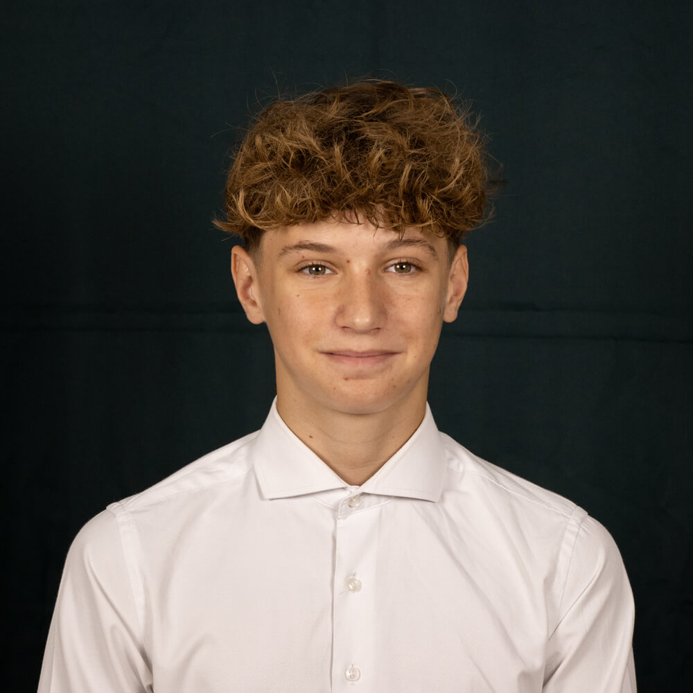 Foto eines jungen Mannes, weisses Hemd, schwarzer Hintergrund. Leon Mehmeti, Lernender Elektroplaner EFZ bei Disch Elektroplanung GmbH in Chur (Graubünden)
